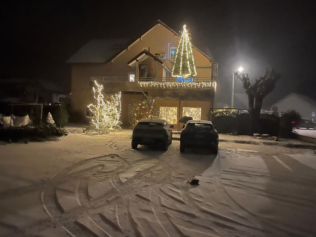 twee auto's geparkeerd voor een huis met kerstverlichting bij L'Hôte du Malsaucy 