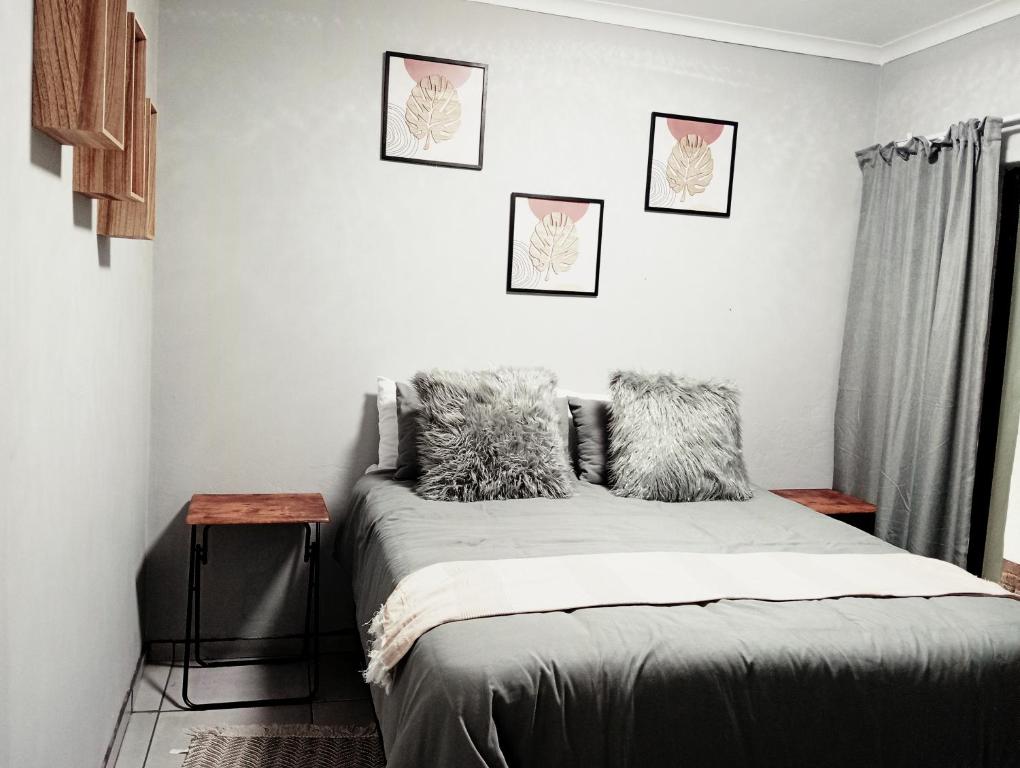 a bedroom with a bed with three pictures on the wall at Be Our Guest Near OR TAMBO International Airport in Boksburg