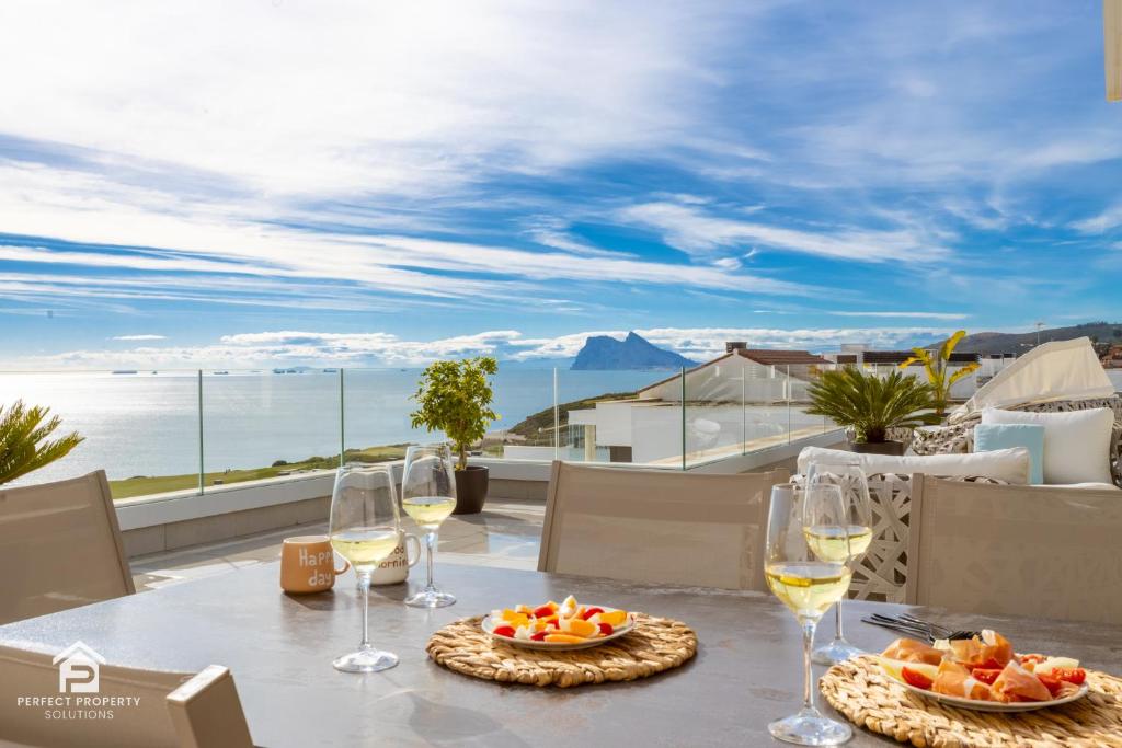 a table with wine glasses and fruit on a balcony at Luxury penthouse with huge terrace and sea and golf views in San Roque
