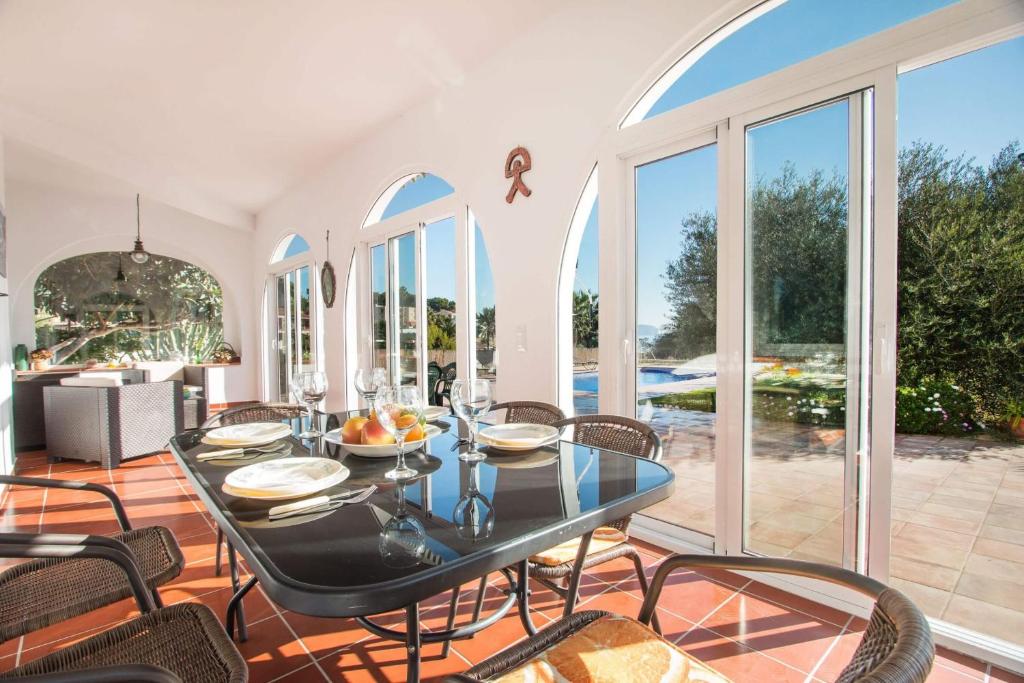 a dining room with a table and chairs and windows at Villa Garlanda - PlusHolidays in Benissa