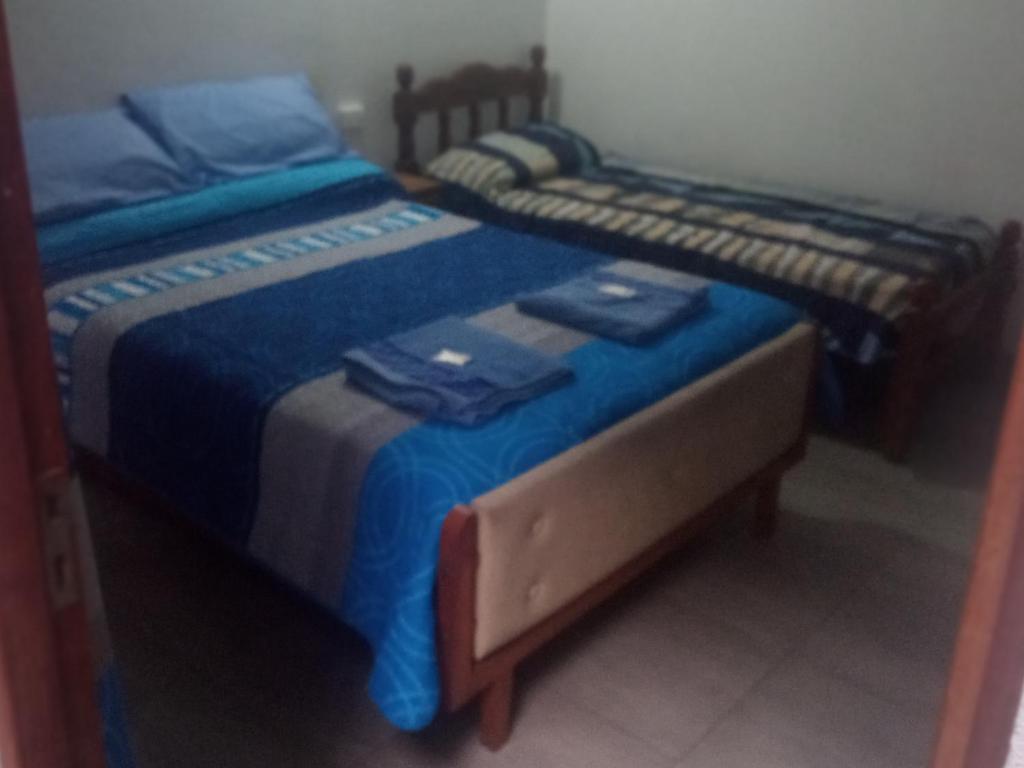 2 Betten in einem Schlafzimmer mit blauer Bettwäsche in der Unterkunft Hostal Tía Dora in San Salvador de Jujuy