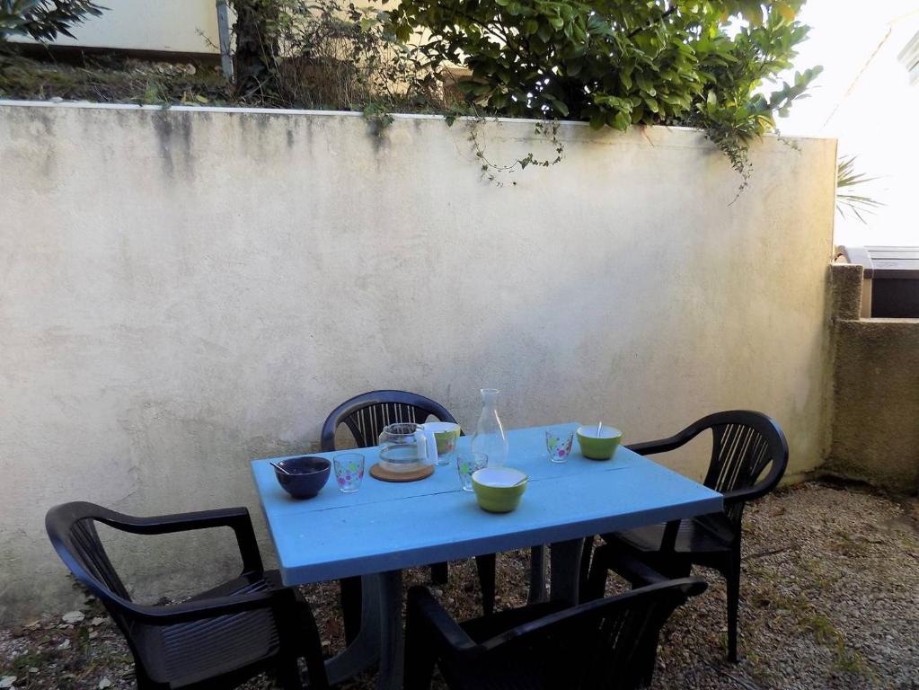 une table bleue avec deux chaises et des bols sur elle dans l'établissement Meschers sur Gironde - VILLA avec TERRASSE - IDEAL vacances en famille, à Meschers-sur-Gironde