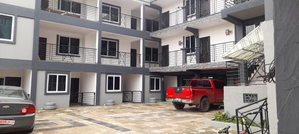 Lovely 2-Bed Apartment in Kaosa في Kasoa: شاحنة حمراء متوقفة أمام مبنى