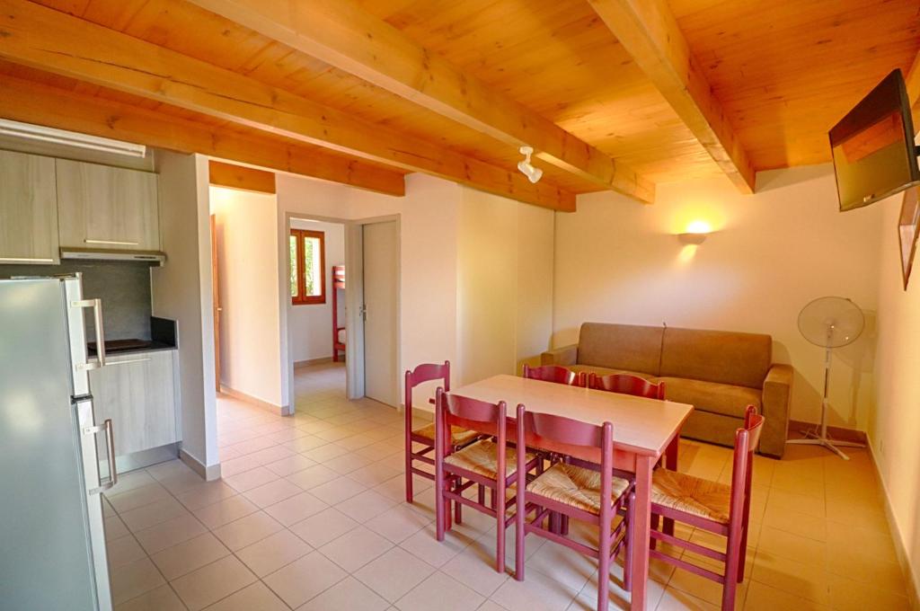 a kitchen and dining room with a table and a couch at Appartement n3 rez de jardin LA LISCIA in Calcatoggio