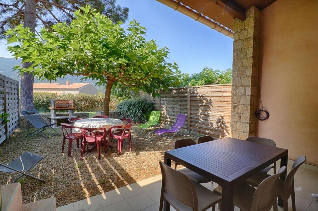 a patio with a table and chairs and a tree at Appartement n3 rez de jardin LA LISCIA in Calcatoggio