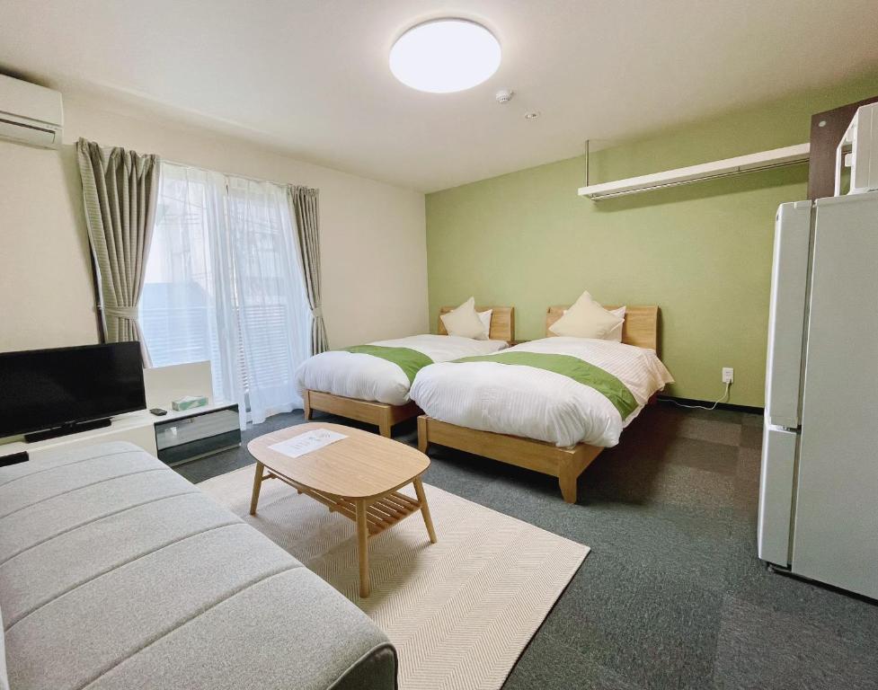 a hotel room with two beds and a tv at Calm Stay Nijo in Kyoto