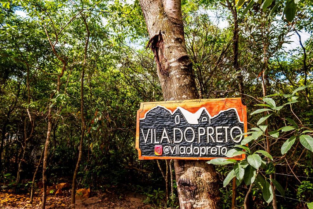 un cartel en un árbol en un bosque en Aconchegante Chale com Wi-Fi no Vale do Capao-BA, en Vale do Capao