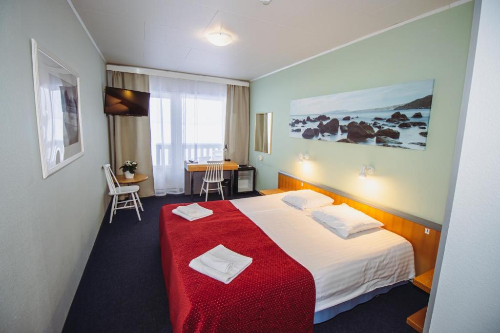 um quarto de hotel com uma cama com um cobertor vermelho em Hotel Promenaadi em Haapsalu