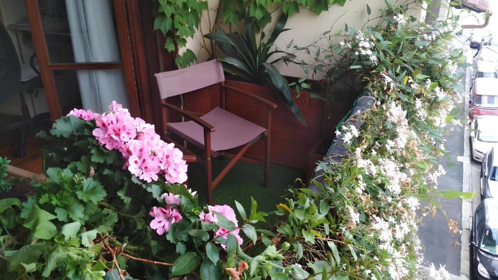 una sedia rosa seduta su un portico con fiori di La casa dei fiori a Firenze