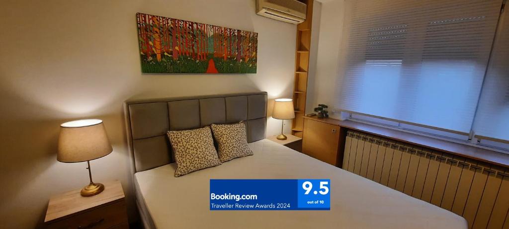 a bedroom with a bed with two lamps and a painting at CityCenter in Belgrade