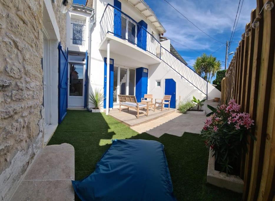 une arrière-cour avec une bâche bleue sur l'herbe dans l'établissement Agréable maison de ville en bord de mer, à Royan