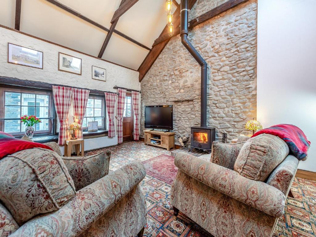 a living room with two couches and a fireplace at Yr Hen Efail in Abergorlech
