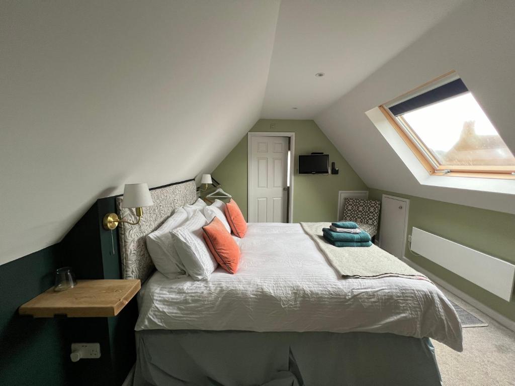 una camera da letto con un letto con cuscini arancioni e una finestra di Cotswold Retreat - Private & Peaceful 