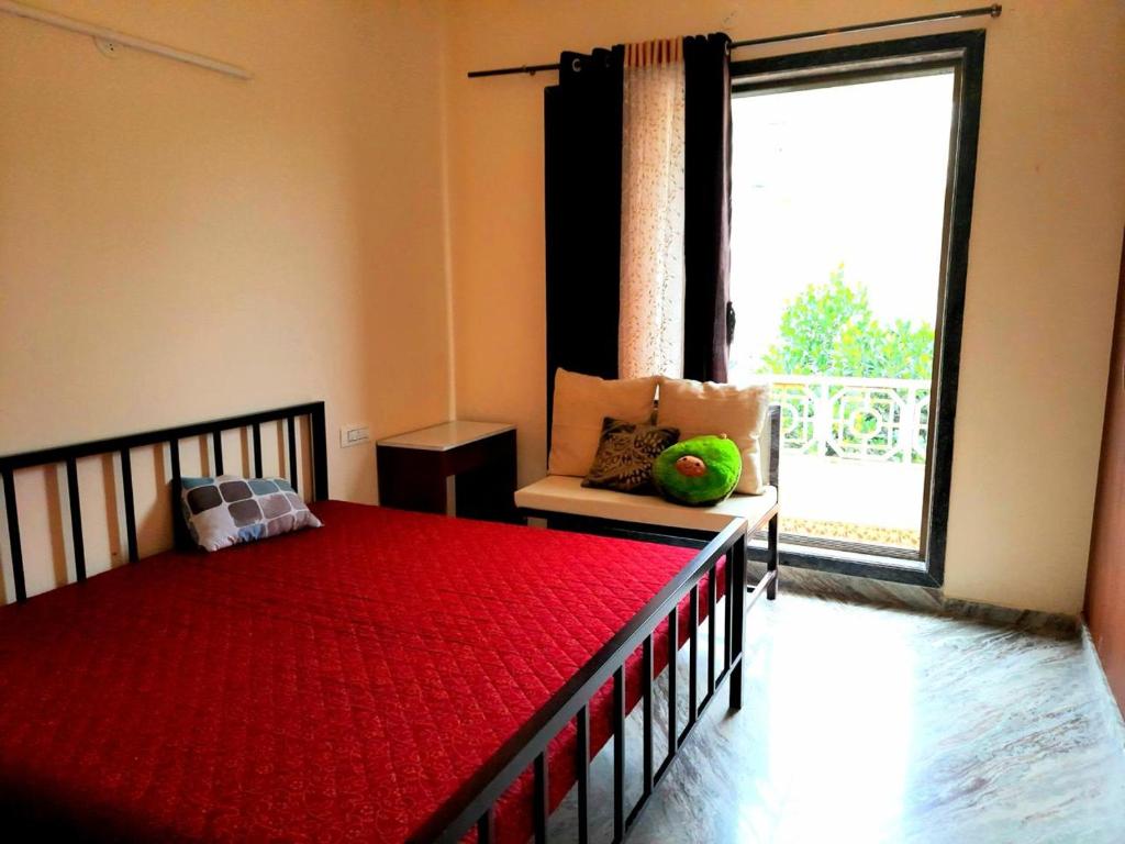 een slaapkamer met een rood bed en een groot raam bij Shiv villa in Saralgaon