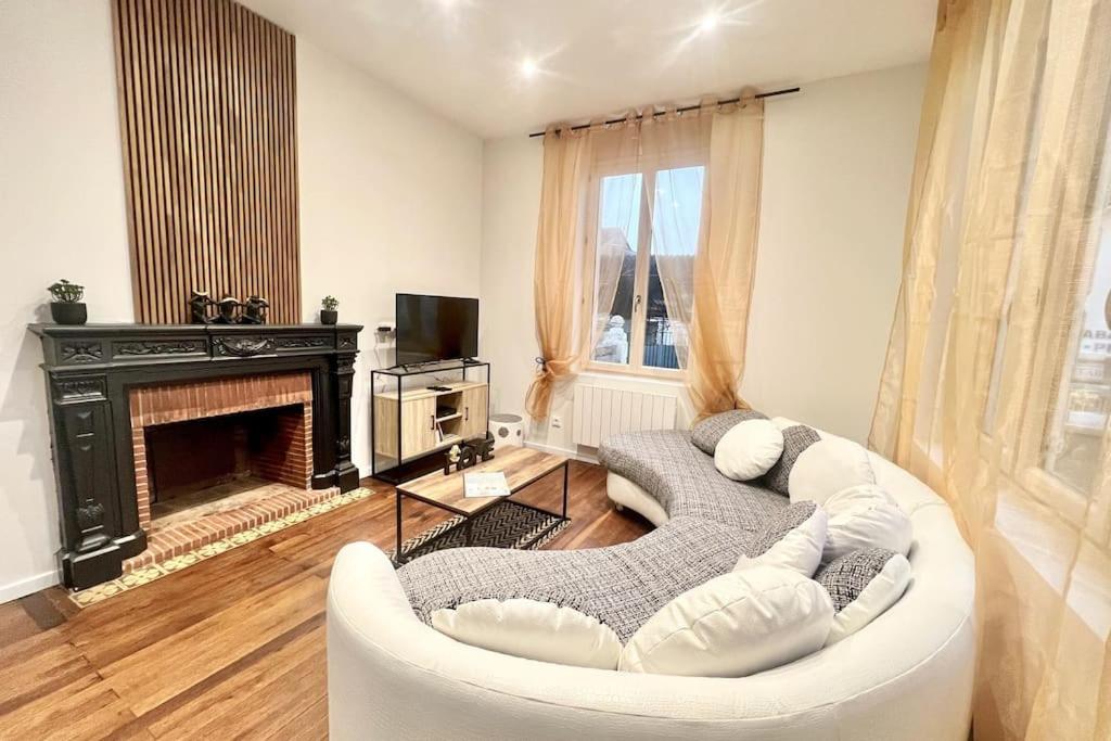 sala de estar con sofá blanco y chimenea en La Ribaudière Maison de ville à 5 min Futuroscope, en Chasseneuil-du-Poitou