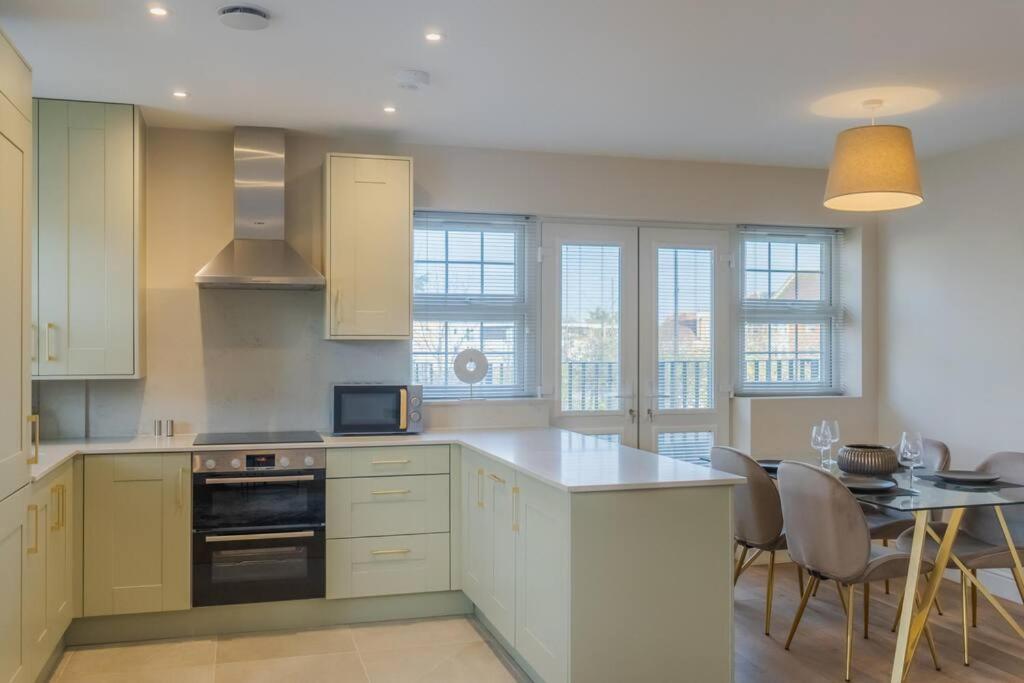 a kitchen with white cabinets and a table with chairs at Cozy 2 Bed Retreat - Allocated Parking in Windsor