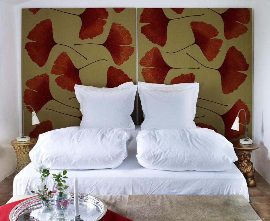 łóżko z białymi poduszkami i ścianą z kwiatami w obiekcie Il Ghiottone Umbro w mieście Todi