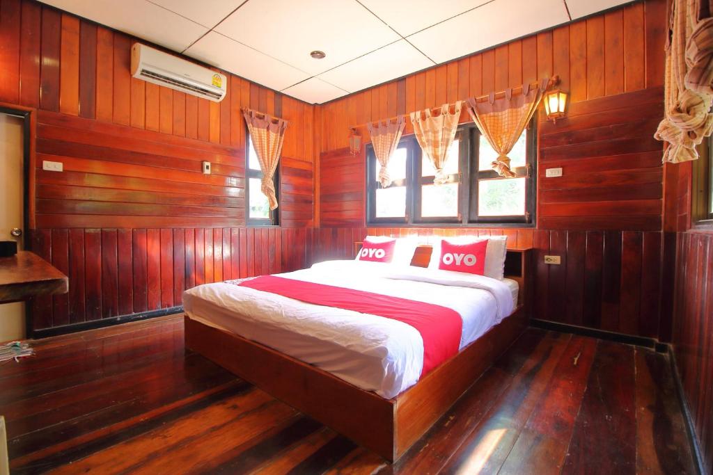a bedroom with a bed with wooden walls and a window at OYO 476 Ban Rimnam Resort in Nakhon Pathom