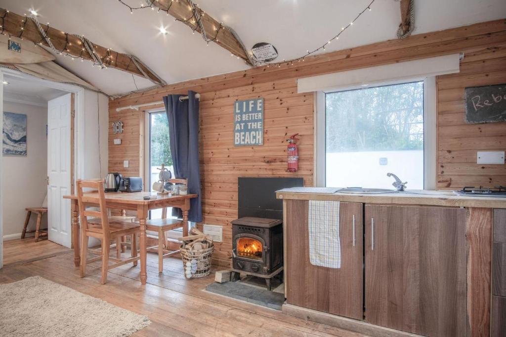 a kitchen with a stove and a table and a fireplace at The Lodge - 1 Bedroom - Freshwest Beach Retreat in Pembroke