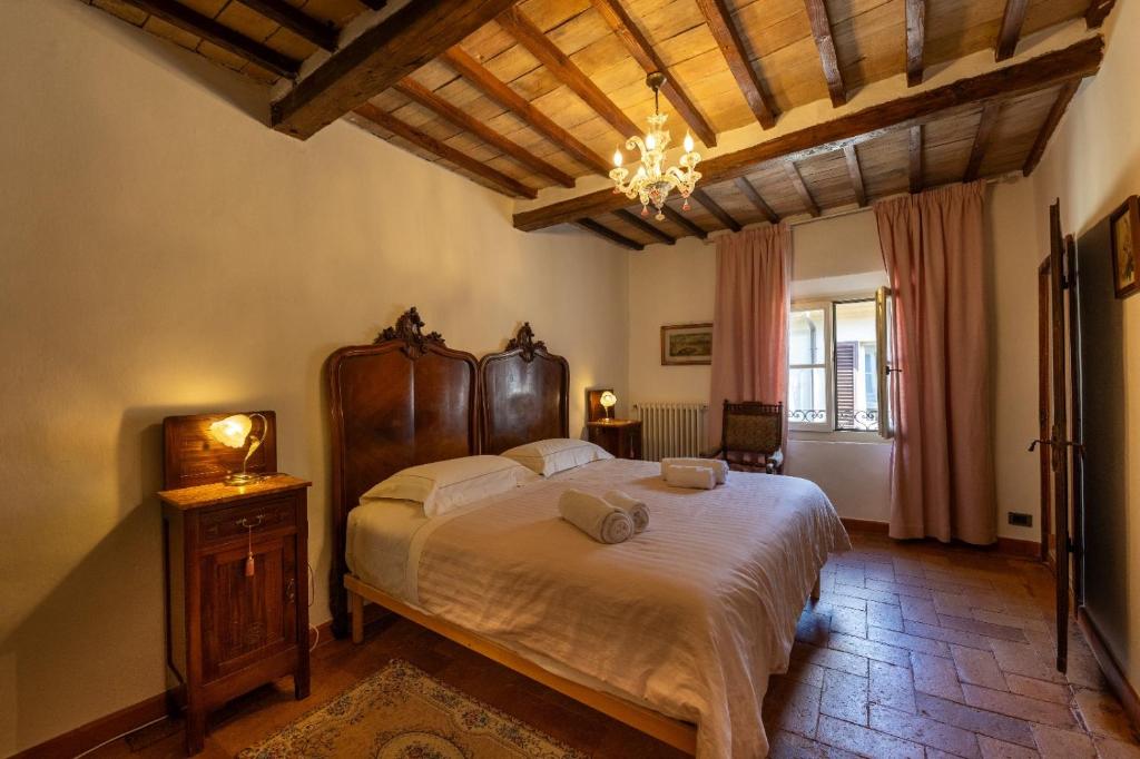 ein Schlafzimmer mit einem großen Bett und einem Kronleuchter in der Unterkunft IL PALAZZO DEL CARDINALE in Montalcino