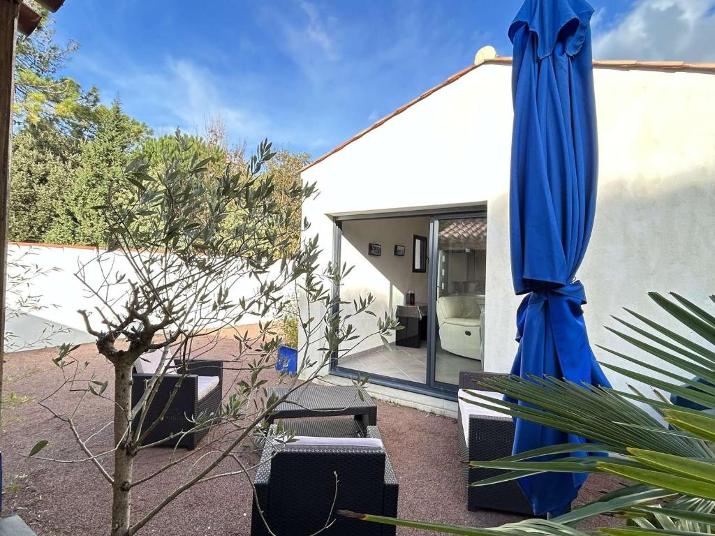 un grand parapluie bleu assis à côté d'un bâtiment dans l'établissement Maison calme avec jardin clos, 800m plage - 2 chambres, BBQ, parking privé, Wifi - FR-1-224B-116, à La Guérinière