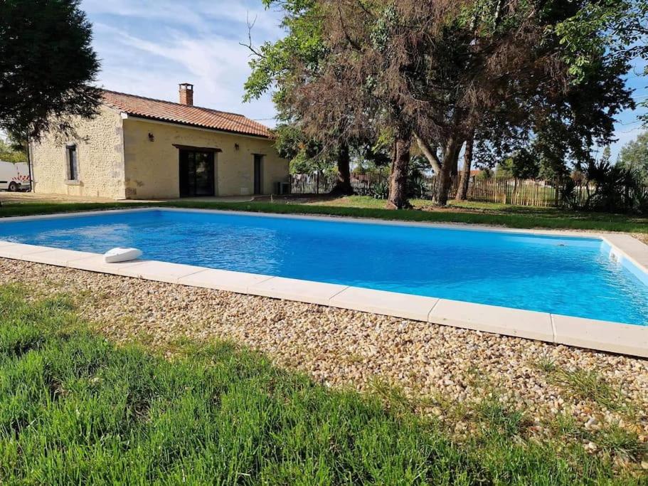 une grande piscine bleue devant une maison dans l'établissement Cottage paisible, à Ribérac