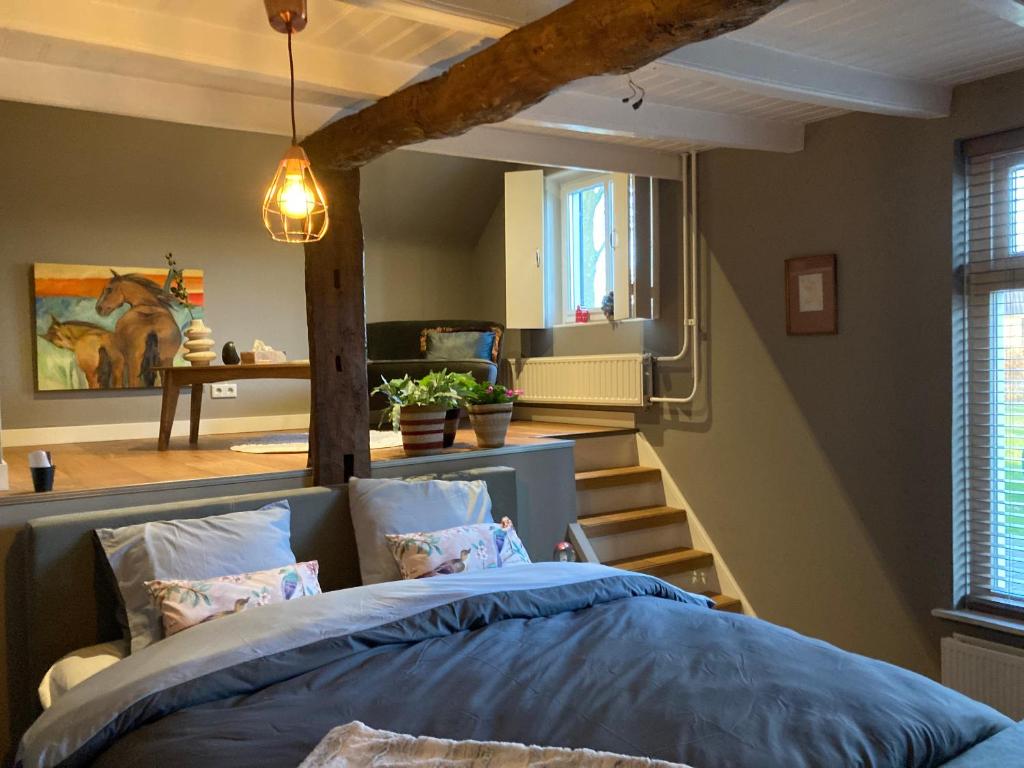 a bedroom with a bed with blue sheets and a staircase at Hoeve bij Vosselen in Asten