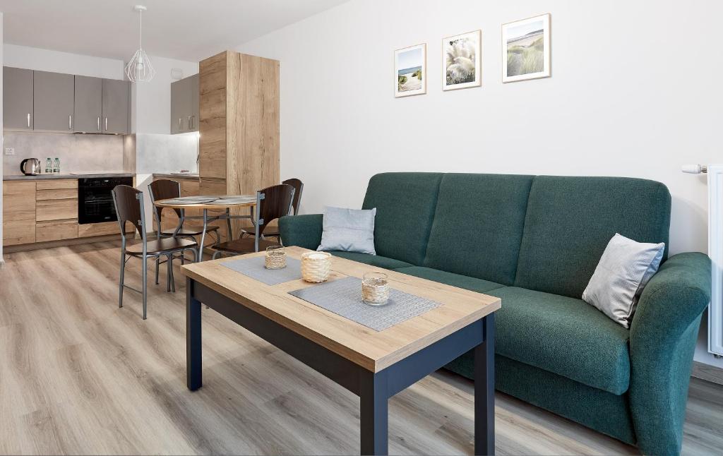 - un salon avec un canapé vert et une table dans l'établissement Poznań Airport Comfy Apartment, à Poznań