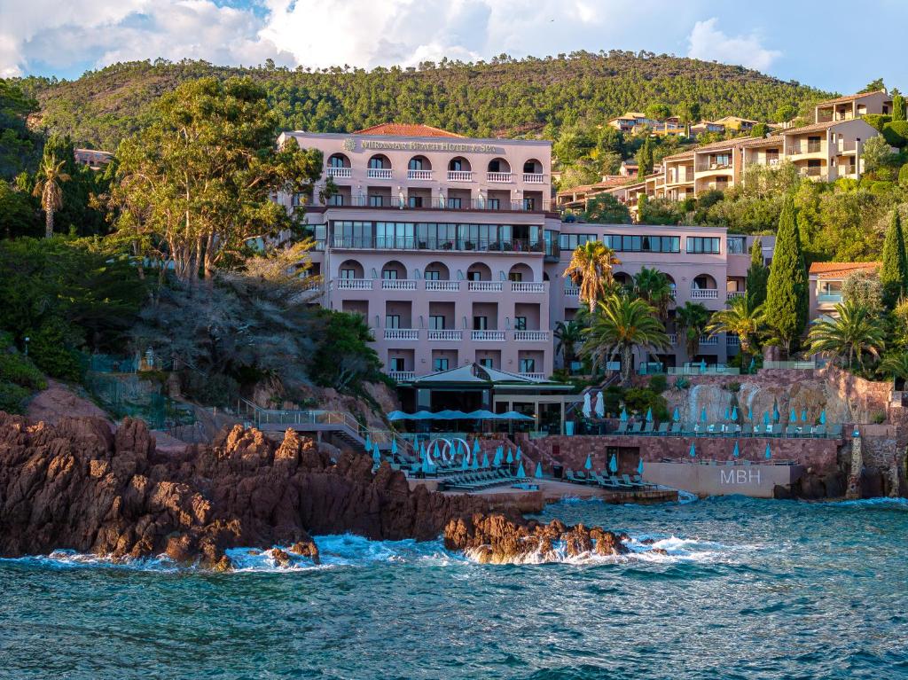 un bâtiment sur la rive d'une masse d'eau dans l'établissement Tiara Miramar Beach Hotel & Spa, à Théoule-sur-Mer