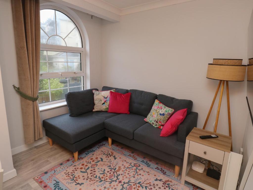 a living room with a gray couch with colorful pillows at 1 Ilsham Cottages in Torquay