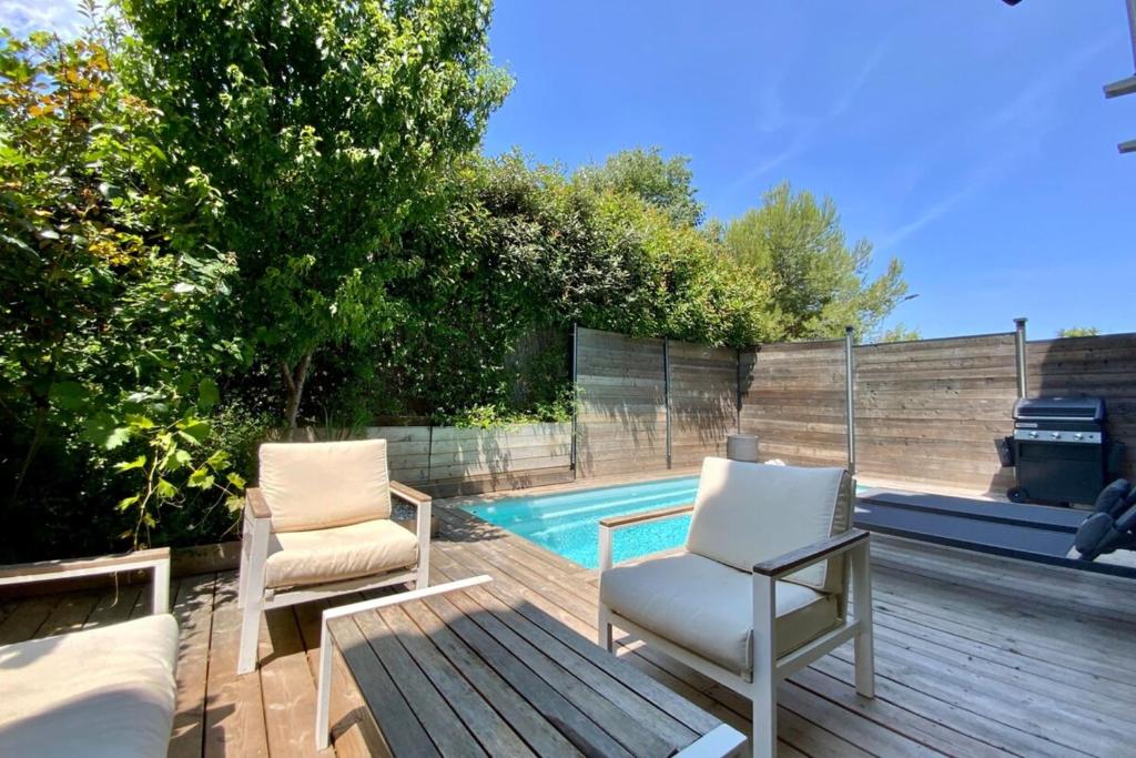 2 sedie sedute su una terrazza accanto alla piscina di Le Lovely - Appartement avec clim et piscine ! a Le Crès