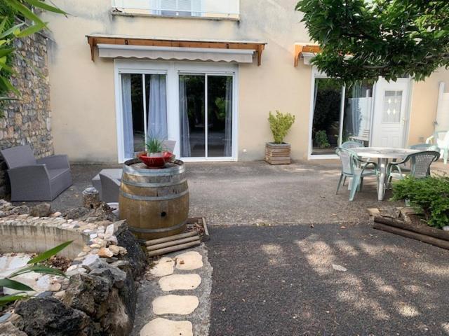 un patio con una mesa y un barril frente a una casa en La musette du Tarn, en Mostuéjouls