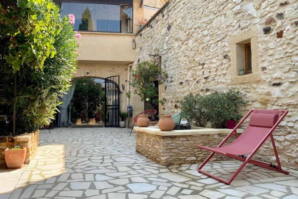 une chaise rose assise dans la cour d'un bâtiment dans l'établissement L'Uzétienne- Large residence with pond and patio!, à Pouzilhac