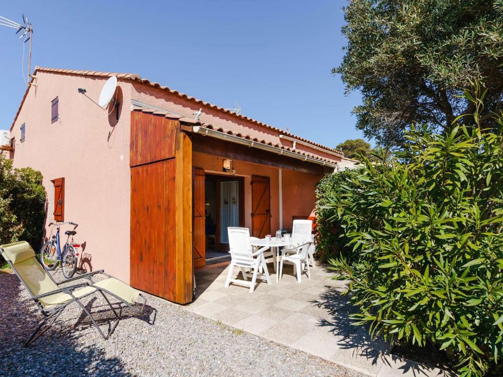 un patio avec une table et des chaises devant une maison dans l'établissement Villa 2 pièces avec mezzanine, terrasse et accès piscine à Gruissan - 5 couchages - FR-1-409-9, à Gruissan