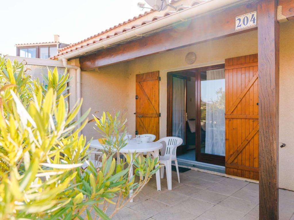 une terrasse avec une table et des chaises dans une maison dans l'établissement Villa 3 pièces avec piscine, terrasse et parking privé - 4 personnes, animaux acceptés - FR-1-409-20, à Gruissan