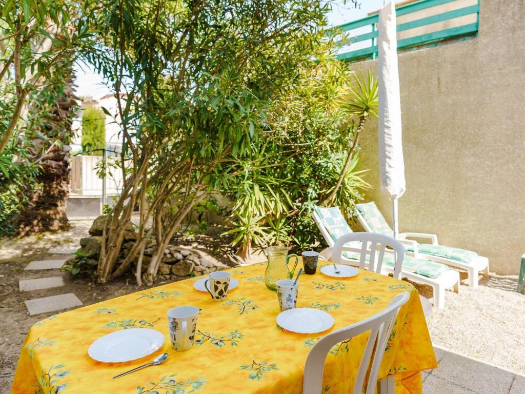 a yellow table with plates and silverware on it at Villa Gruissan, 3 pièces, 4 personnes - FR-1-409-31 in Gruissan