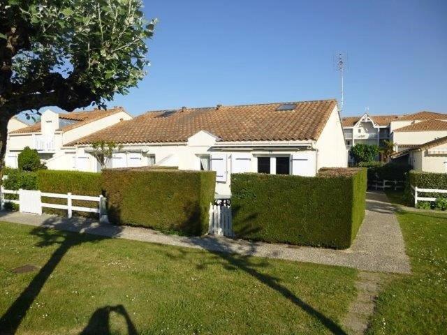 a person standing in front of a white house at Vaux sur Mer - côté PONTAILLAC - VILLA MITOYENNE - PISCINE COLLECTIVE in Vaux-sur-Mer