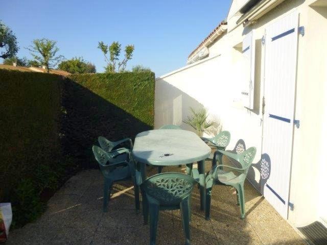 a patio with a table and chairs next to a building at Vaux sur Mer - côté PONTAILLAC - VILLA MITOYENNE - PISCINE COLLECTIVE in Vaux-sur-Mer