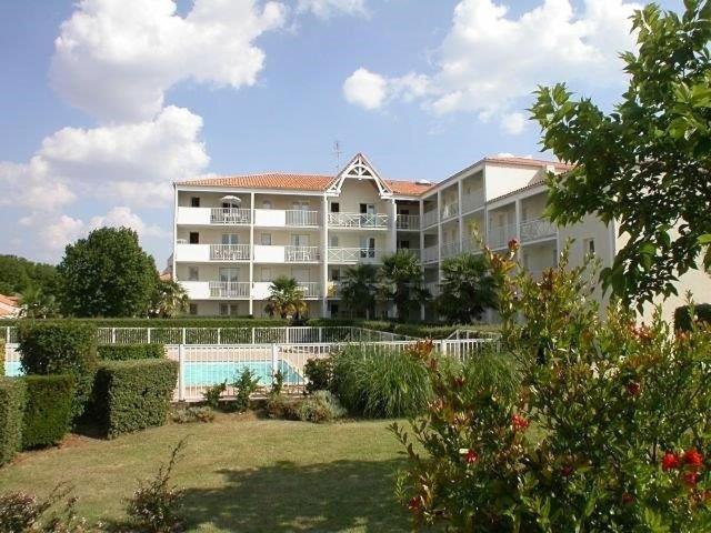 a large building with a swimming pool in front of it at Vaux sur Mer - côté PONTAILLAC - VILLA MITOYENNE - PISCINE COLLECTIVE in Vaux-sur-Mer