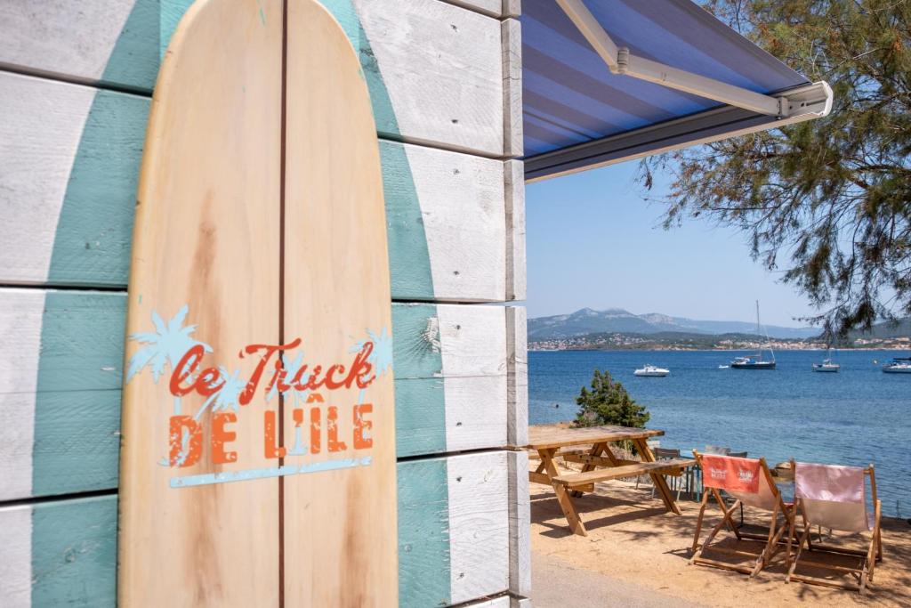 a wooden surfboard leaning against a building with a table and chairs at Hôtel Helios &amp; SPA - Ile des Embiez in Six-Fours-les-Plages