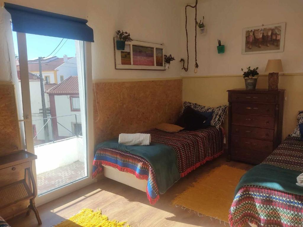 a bedroom with a bed next to a window at Casa Girassol in Santiago do Cacém