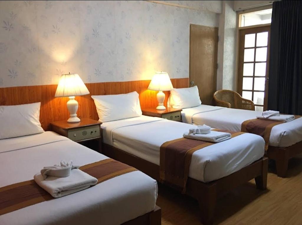une chambre d'hôtel avec 3 lits et 2 lampes dans l'établissement 12PM Bangkok, à Bang Kapi