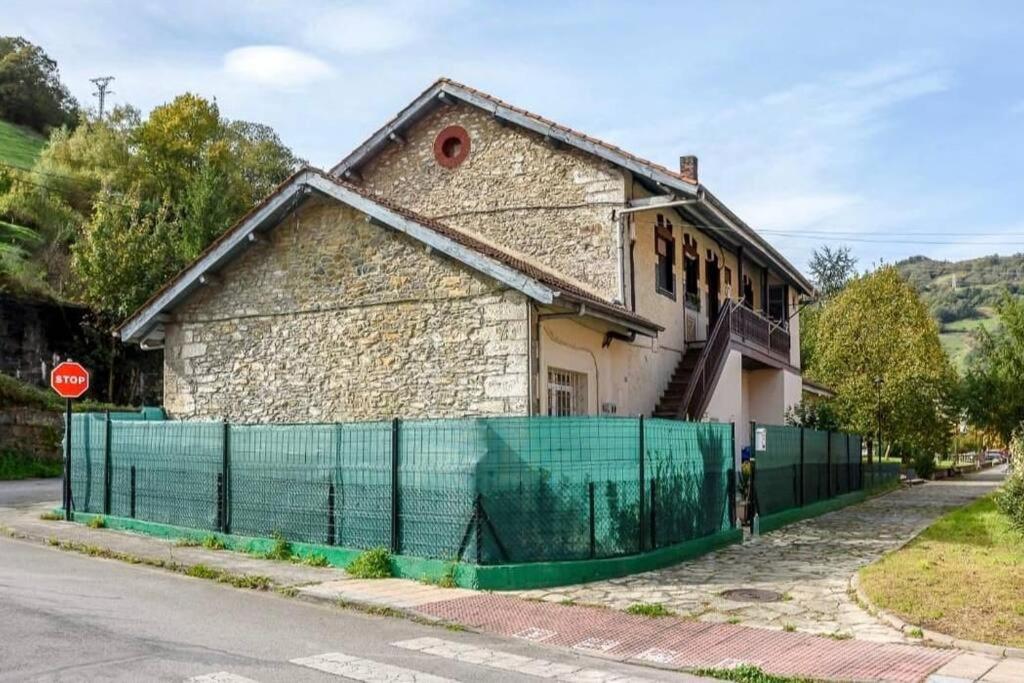 een huis met een groen hek naast een straat bij El Caserón de Hullera in Cárabanzo