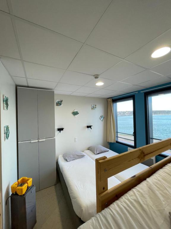 a bedroom with two beds and a large window at CLLCM - Club Leo Lagrange de Camaret-sur-Mer in Camaret-sur-Mer