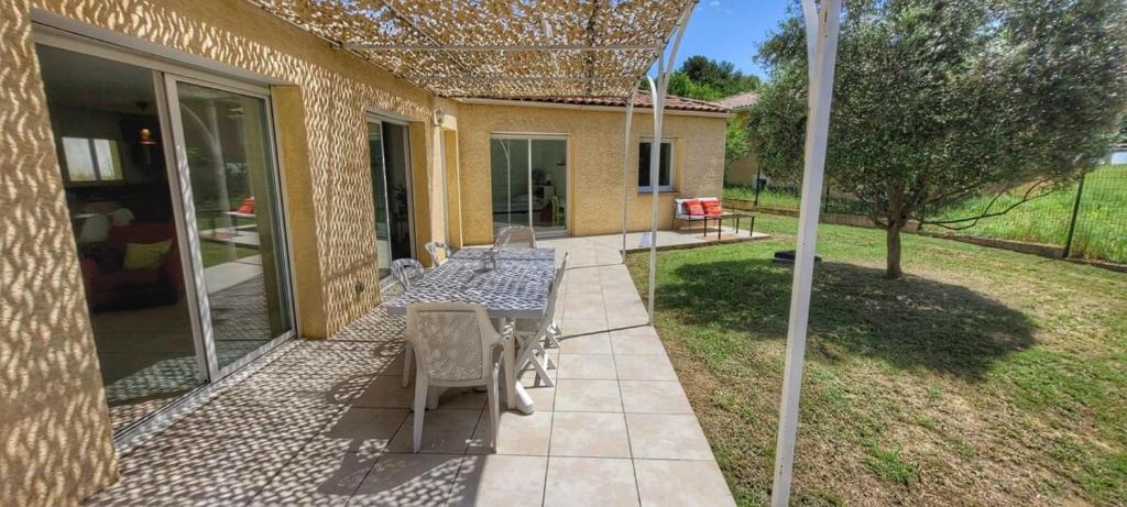 a patio with a table and chairs in a yard at La tranquillle - Villa with garden in Montpellier! in Montpellier
