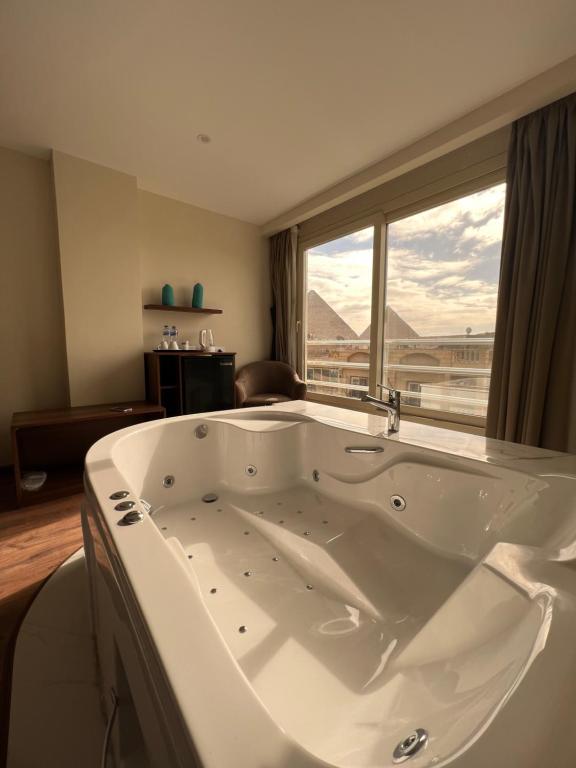 a large white bath tub in a room with a window at The Home Boutique Hotel Pyramids Inn in Cairo