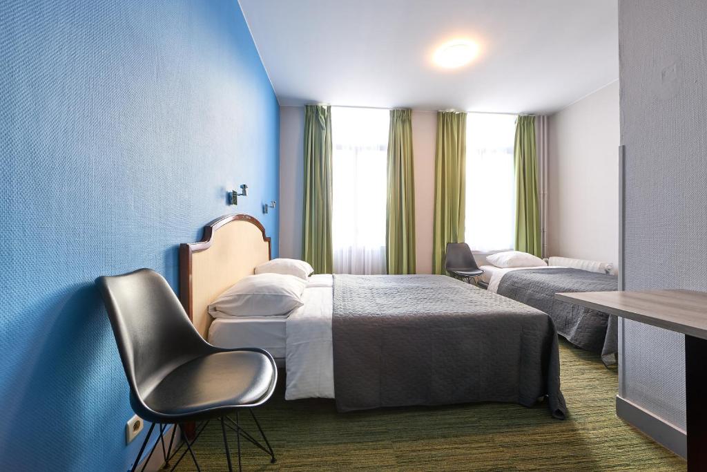 een hotelkamer met 2 bedden en een blauwe muur bij Hotel Derby MERODE in Brussel