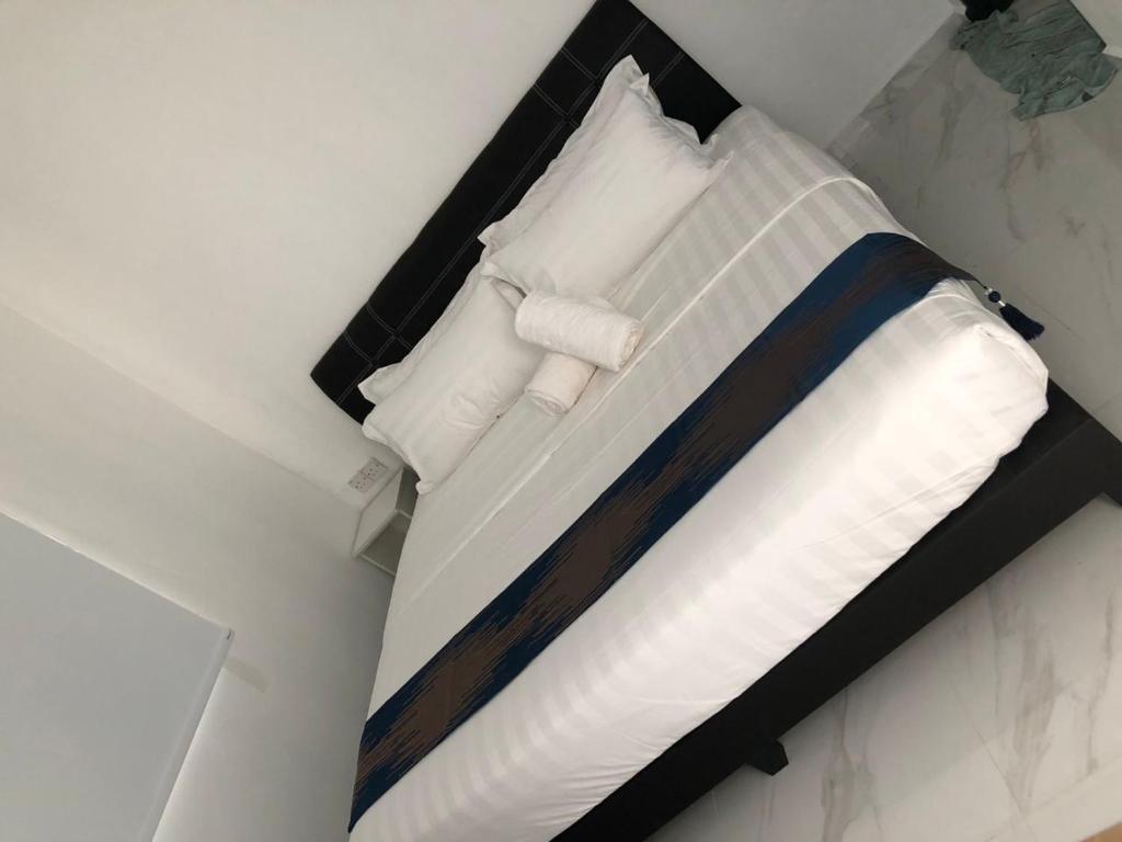 uma cama com lençóis brancos e almofadas num quarto em SAMMY HOOMESTAY em Ipoh