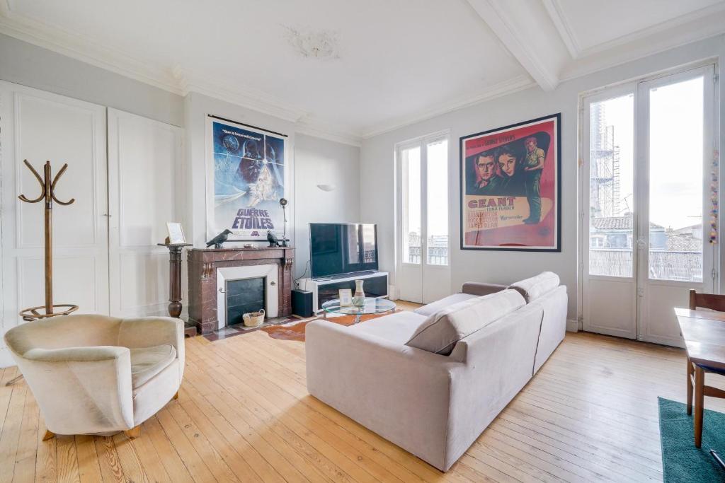 un salon avec un canapé blanc et une cheminée dans l'établissement LE VICTOR - Grand et lumineux T3, à Bordeaux