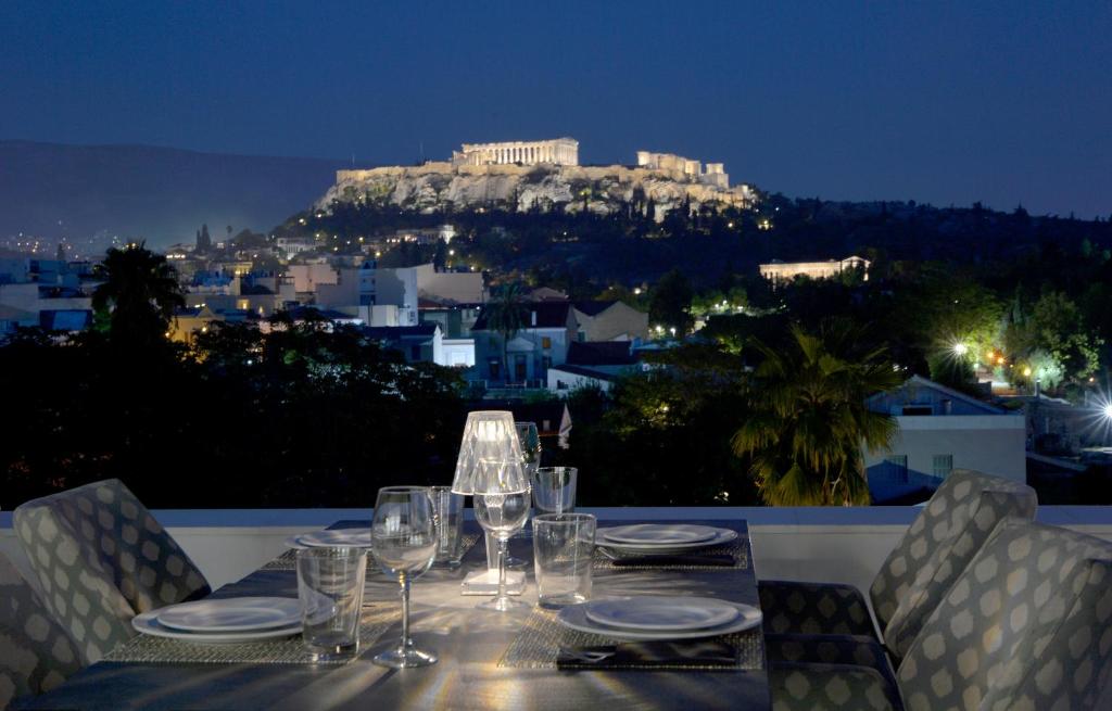 雅典的住宿－Athenaeum Eridanus Luxury Hotel，一张带酒杯的桌子,享有雅典卫城的景色
